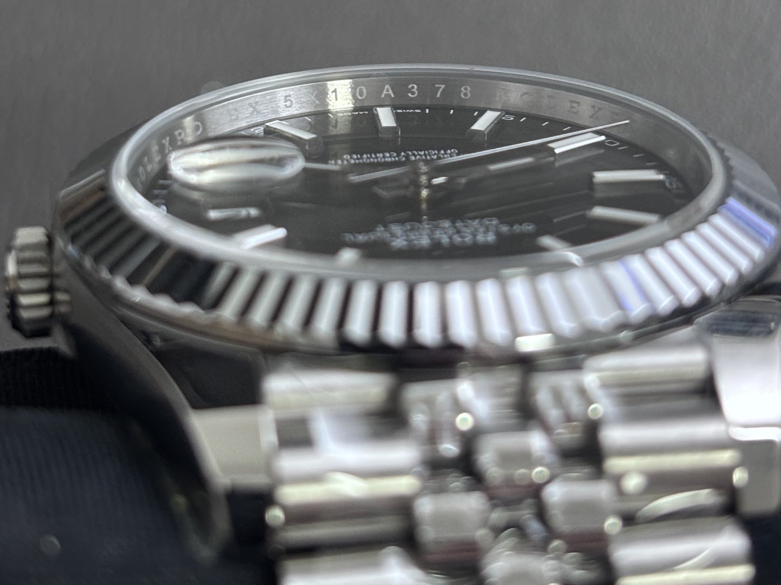 Rolex Datejust photographed from the side, angled so the serial number 5X10A378 engraved on the rehaut is legible